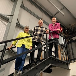 Lewis, Kingsley and Annie standing on stairs in warehouse setting